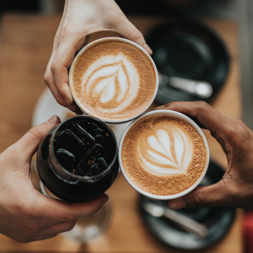 close up of hands holding coffee cups together